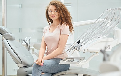 Woman in pink shirt sitting in dental chair and smiling