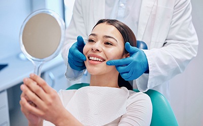 Female dental patient looking at handheld mirror