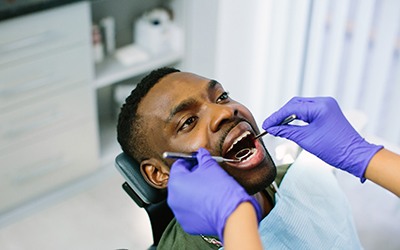 Dentist examining a male patient’s smile