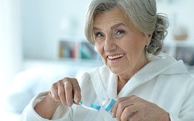 Senior woman squeezing toothpaste onto her toothbrush