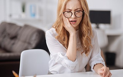 Woman with glasses experiencing pain in tooth