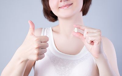 Woman giving thumbs up and holding a tooth in Wayland, MA