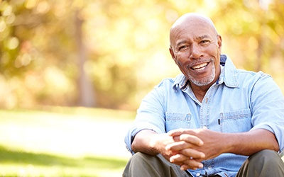 Older man sitting outside and smiling
