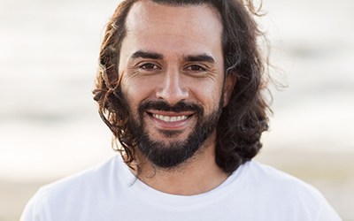 Close-up of a bearded man smiling on a beach