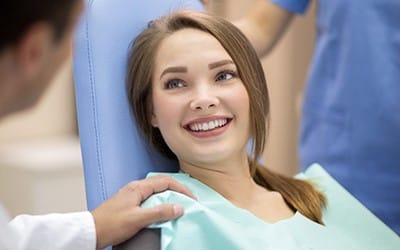 A woman listening to a dentist speak to her.