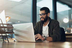 Man with glasses working on laptop at office