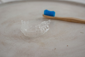 Invisalign clear aligner sitting next to toothbrush on counter