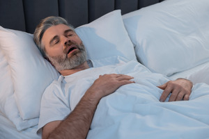 Close-up of man snoring in bed due to sleep apnea
